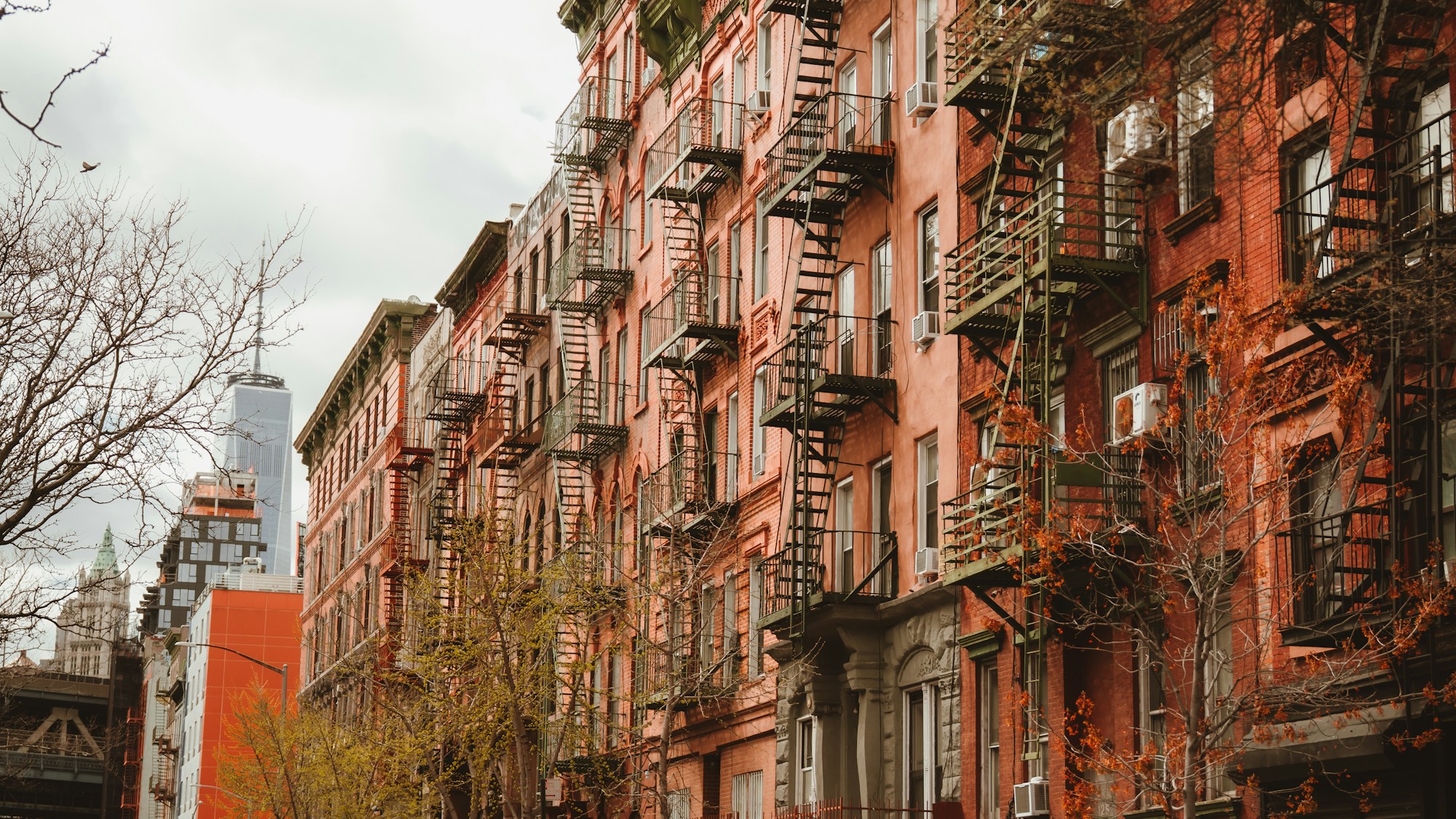 Lower Manhattan walk-up buildings with fire escapes, One World Trade Center in the distance